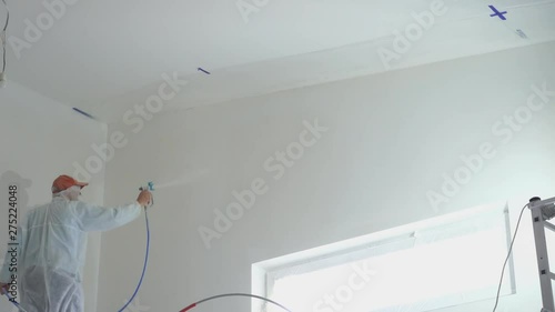 repair of the apartment - professional painter paints the walls with white paint spray gun
