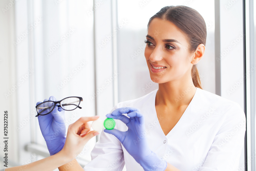 Vision concept. Eye doctor choosing between eyeglasses and lenses standing in front of the eye chart in the cabinet Vision concept. Eye doctor choosing between eyeglasses and lenses standing in front of the eye chart in the cabinet