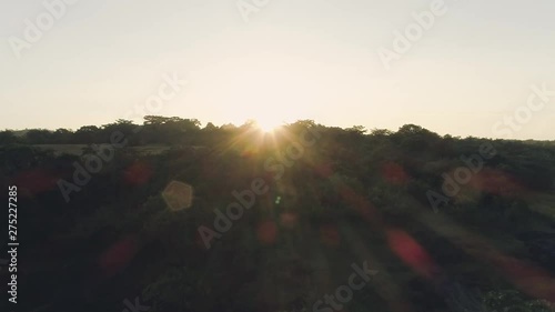 Drone footage of landscape and a field with revealing sun glare during a sunrise. photo