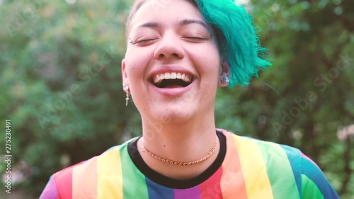 cheerful young lesbian woman smiling to the camera. Portrait of a gay young woman wearing the rainbow colors of the iconic gay flag.