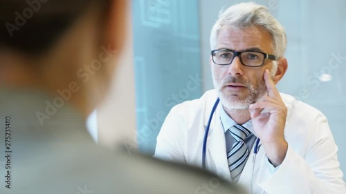 Mature doctor talking to patient in modern clinic