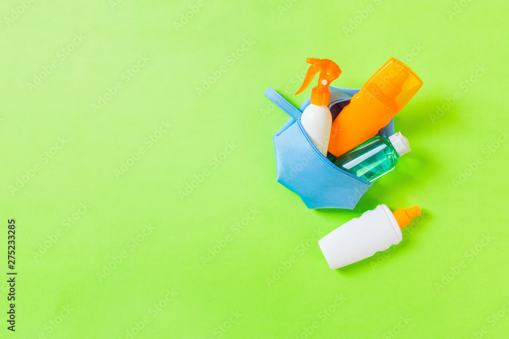 Top view of female cosmetics bag full of suncream spray, sunsreen, sunblock and body lotion and spf cream on green background with copy space. Directly above. Bright summer concept Top view of female cosmetics bag full of suncream spray, sunsreen, sunblock and body lotion and spf cream on green background with copy space. Directly above. Bright summer concept