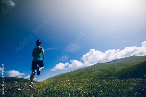 Woman trail runner running up on grassland mountain