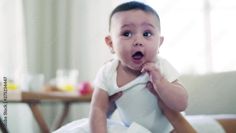 A young affectionate mother cuddling with a baby indoors on bed. A young affectionate mother cuddling with a baby indoors on bed.