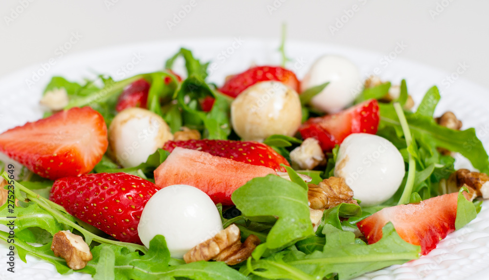 Salad with mozzarella cheese, arugula and strawberries on a white plate. Healthy summer green salad for diet, snack or light dinner. Salad with mozzarella cheese, arugula and strawberries on a white plate. Healthy summer green salad for diet, snack or light dinner.