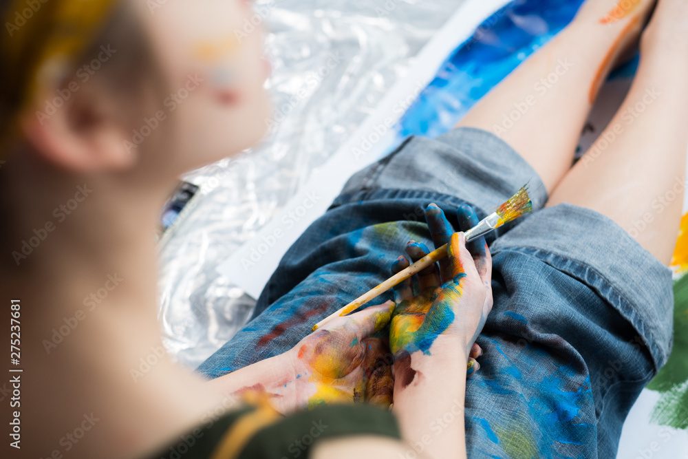 Inspiration and creativity. Cropped shot of female artist taking break, sitting with hands and jeans dirty with colorful paint.