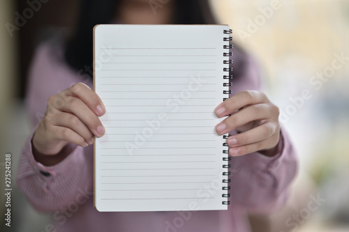 Cropped shot of Young girl showing blank white notebook in hands