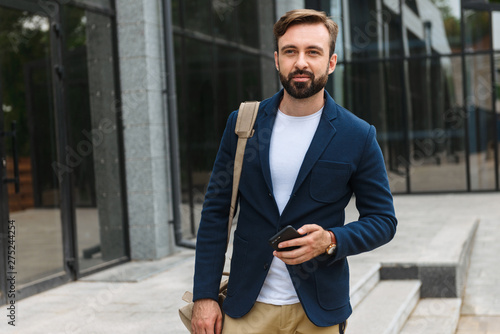 Attractive young bearded man wearing jacket walking
