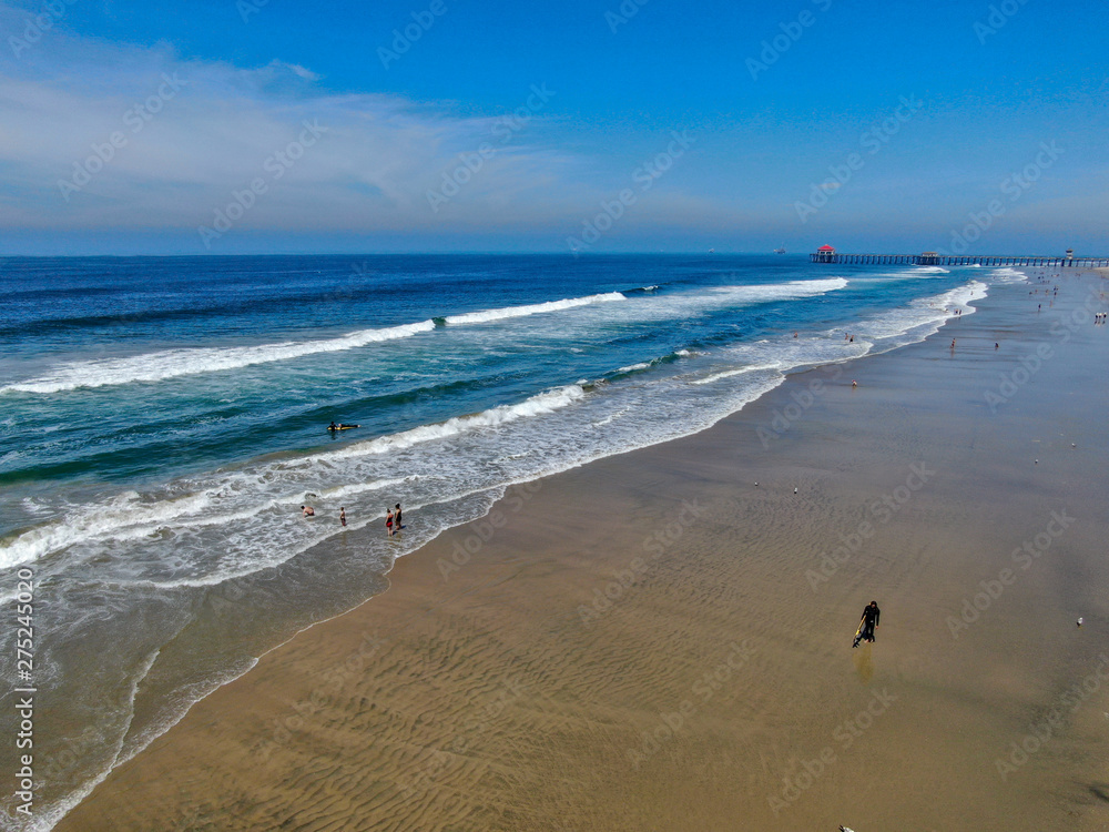Aerial view people enjoying the beach during sunny day. Huntington Beach, Southeast Los Angeles, California. USA