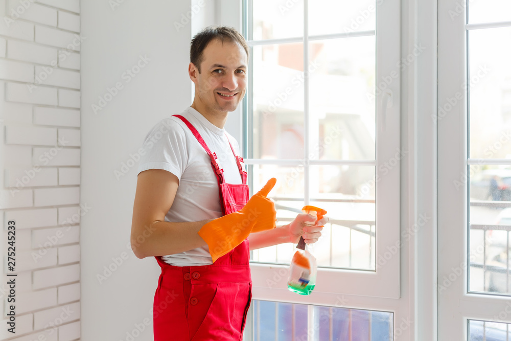 Young man cleaning window in office Young man cleaning window in office