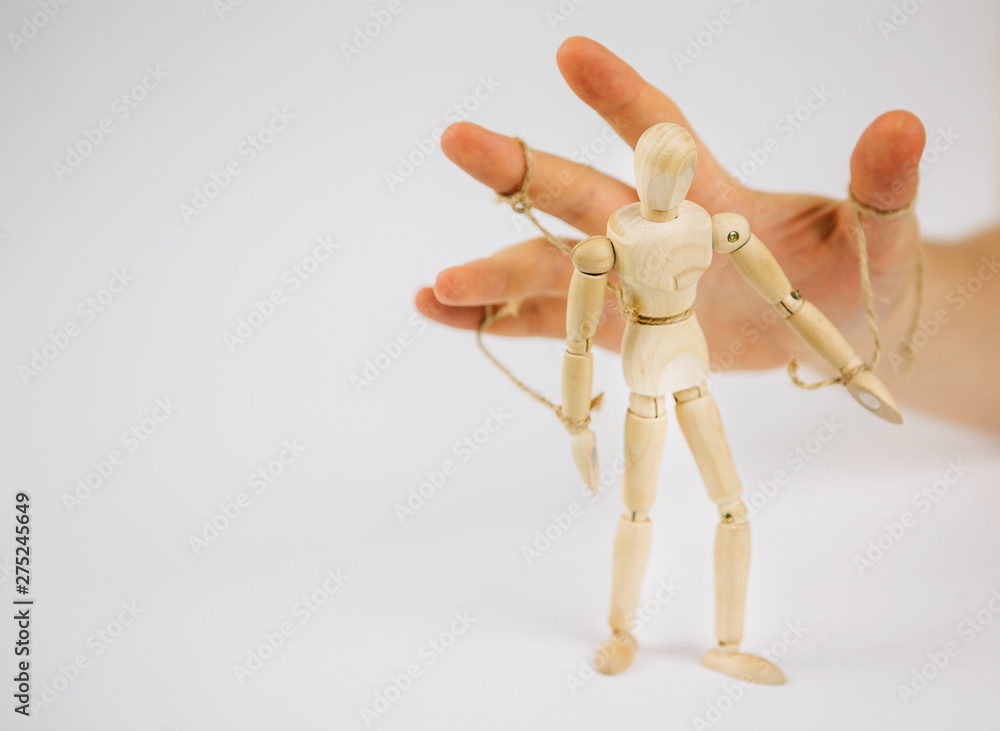 Manipulation of wooden puppet.Puppeteer. The hand controls the puppet strings. Manipulation of the people.people. Manipulation of wooden puppet.Puppeteer. The hand controls the puppet strings. Manipulation of the people.people.