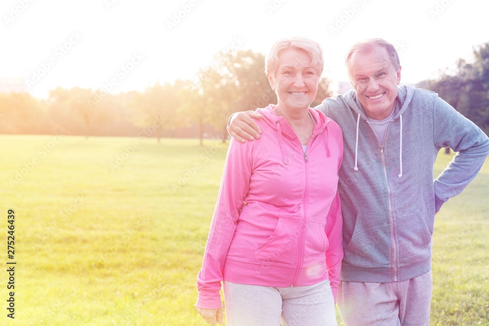 Cheerful senior man and woman in sportswear standing at park Cheerful senior man and woman in sportswear standing at park