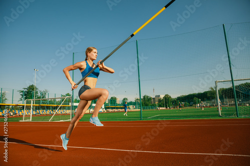 Professional female pole vaulter training at the stadium in sunny day. Fit female model practicing in high jumps outdoors. Concept of sport, activity, healthy lifestyle, action, movement, motion. © master1305