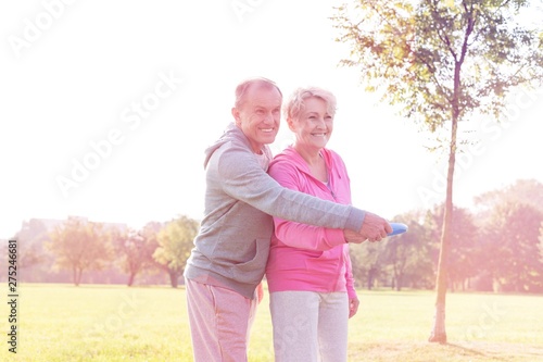 Loving active couple throwing flying disc together in park