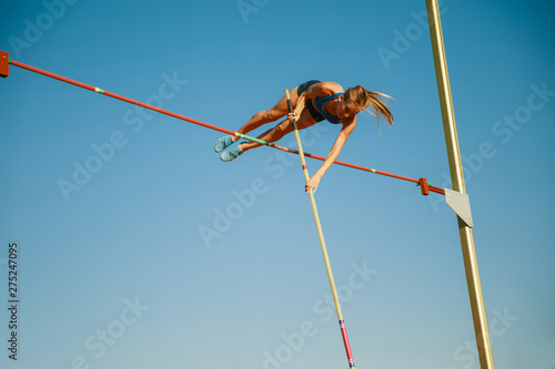 Slika na platnu Professional female pole vaulter training at the stadium in sunny day