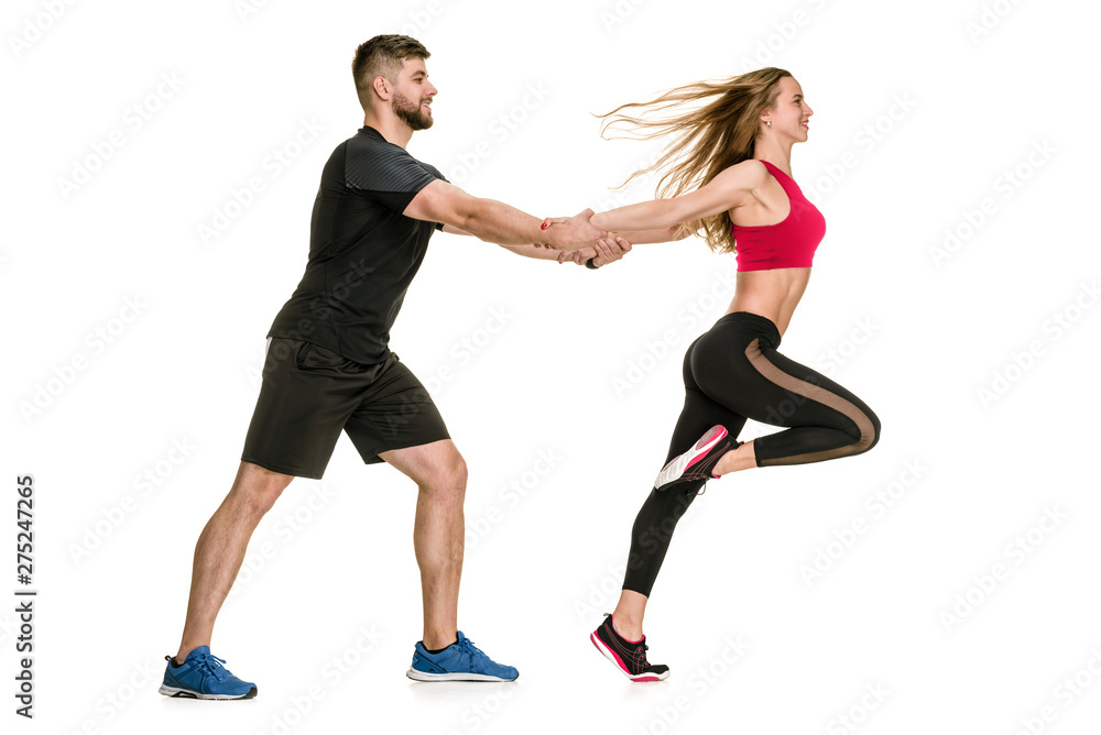 Side view of happy athletic couple training on white background