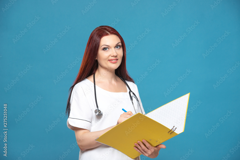 Family female woman doctor with a stethoscope holds folder with documents, has friendly expression, isolated blue background. Medicine concept Family female woman doctor with a stethoscope holds folder with documents, has friendly expression, isolated blue background. Medicine concept