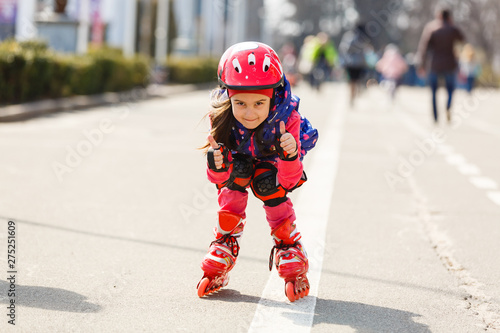 Wallpaper Mural Funny Little pretty girl on roller skates in helmet riding in a park. Healthy lifestyle concept Torontodigital.ca