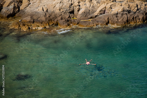 Aerial view of a person swimming in torquoise ocean