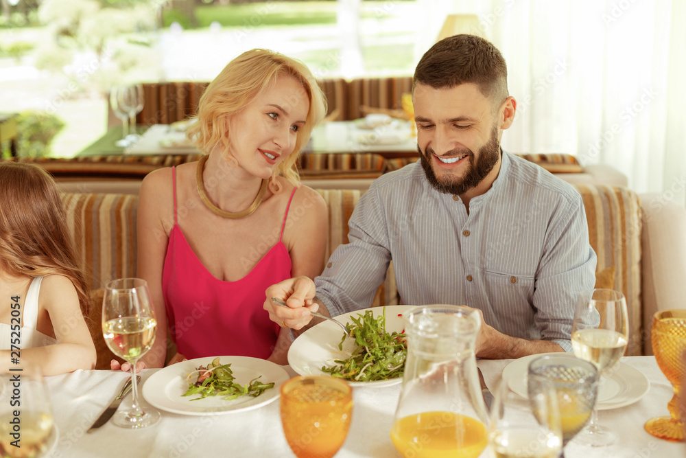 Handsome bearded husband treating his wife giving her some salad Handsome bearded husband treating his wife giving her some salad