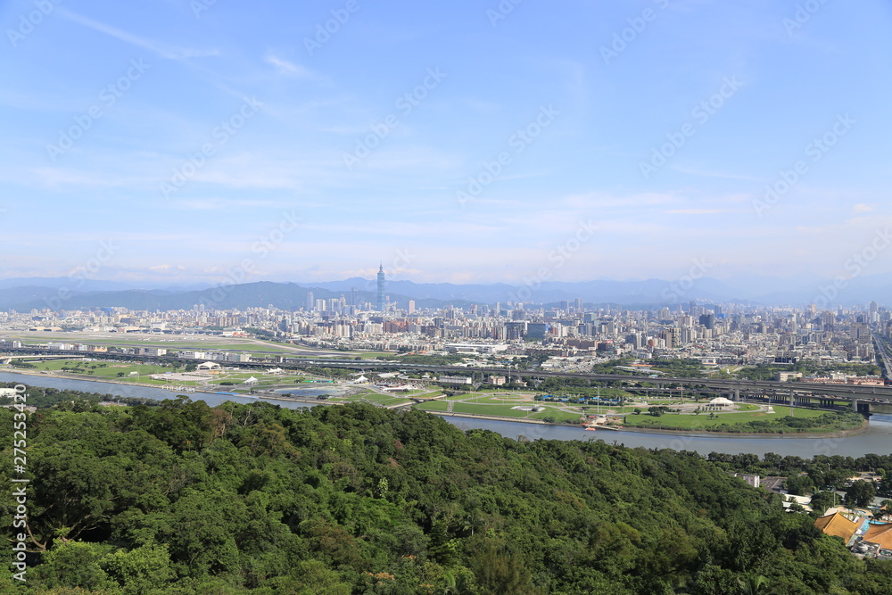Obraz premium Taipei, Taiwan. Jun 2019. The Taipei 101 landmark building rising above generic architecture in the city of Taipei Taiwan on a sunny day as seen from Jian Tan Mountain.