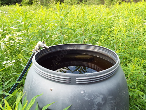 water in a barrel on a background of green grass on a glade