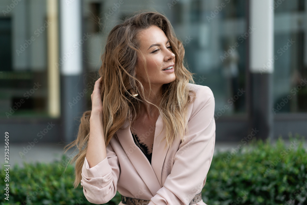Street portrait of a European girl with long flowing hair in a pink jacket. Lifestyle Natural makeup. The face of the advertising company Street portrait of a European girl with long flowing hair in a pink jacket. Lifestyle Natural makeup. The face of the advertising company