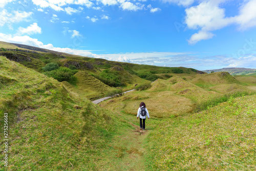 Female tourist hiking the Fairy GLen in the sunny day in summer , Uig , Scotland
