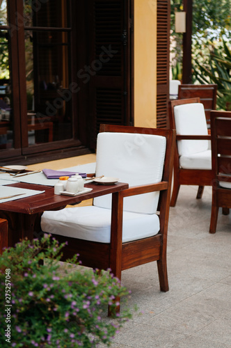 Outdoor wooden chairs dinner table and flower bush