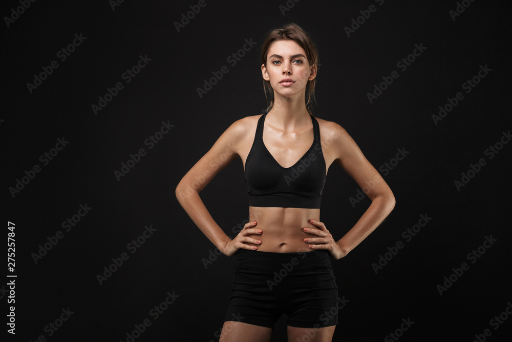 Portrait of focused caucasian woman in sportswear standing with arms on waist during workout in gym Portrait of focused caucasian woman in sportswear standing with arms on waist during workout in gym