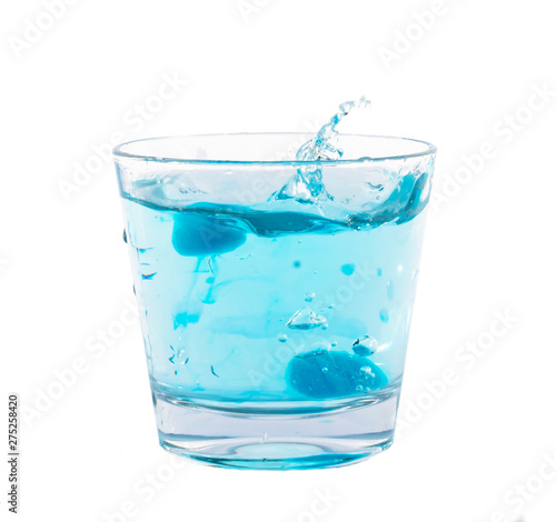 Blue ice cubes splashing into glass of water.