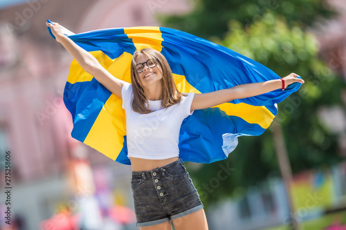 Fototapete Happy girl tourist walking in the street with sweden flag