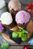 Assorted three types of ice cream in a waffle cone. Chocolate, berry and vanilla ice cream. A refreshing summer dessert. Vertical photo. Selective focus.