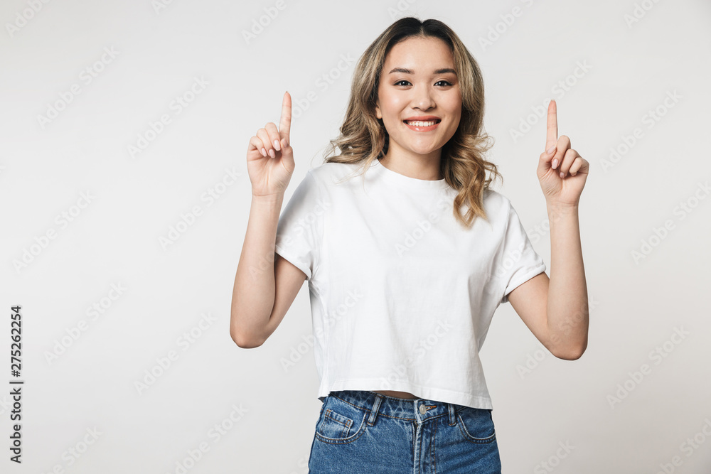Happy cute young woman posing isolated over white wall background pointing. Happy cute young woman posing isolated over white wall background pointing.