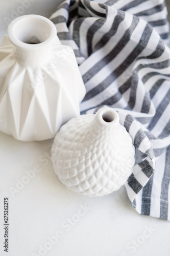 Two white ceramic vases and striped cloth on white background
