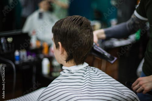 A young successful hairdresser, making an attractive man's haircut in a hairdresser. to cut long hair. man's haircut