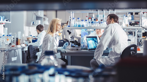 Group of Research Scientists in White Coats are Working and Having Discussion in a Modern High-Tech Laboratory. Genetics and Pharmaceutical Studies and Researches.