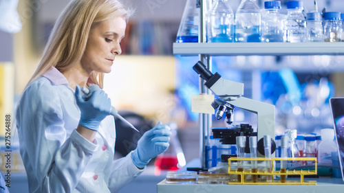 Blond Research Genetic Woman Scientist is Holding a Micro Pipette and Preparing Sample for Microscope Analyzis and Testing in a Modern High-Tech Laboratory.