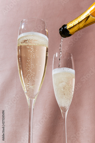 Prosecco flutes and a bottle, an italian sparkling wine on pink romantic background