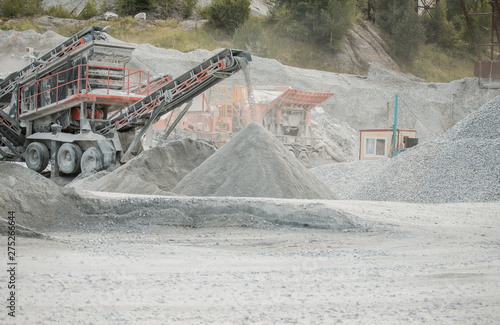 Cement production factory on mining quarry. Conveyor belt of heavy machinery loads stones and gravel. Industrial background with working gravel crusher photo