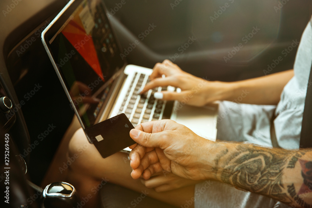 Young couple preparing for vacation trip on the car in sunny day. Woman and man sitting and ready for going to sea, riverside or ocean. Concept of relationship, vacation, summer, holiday, weekend.