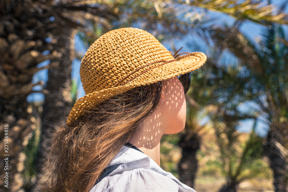 Back view on the Woman in the straw hat walking in the palm forest. Seychelles islands