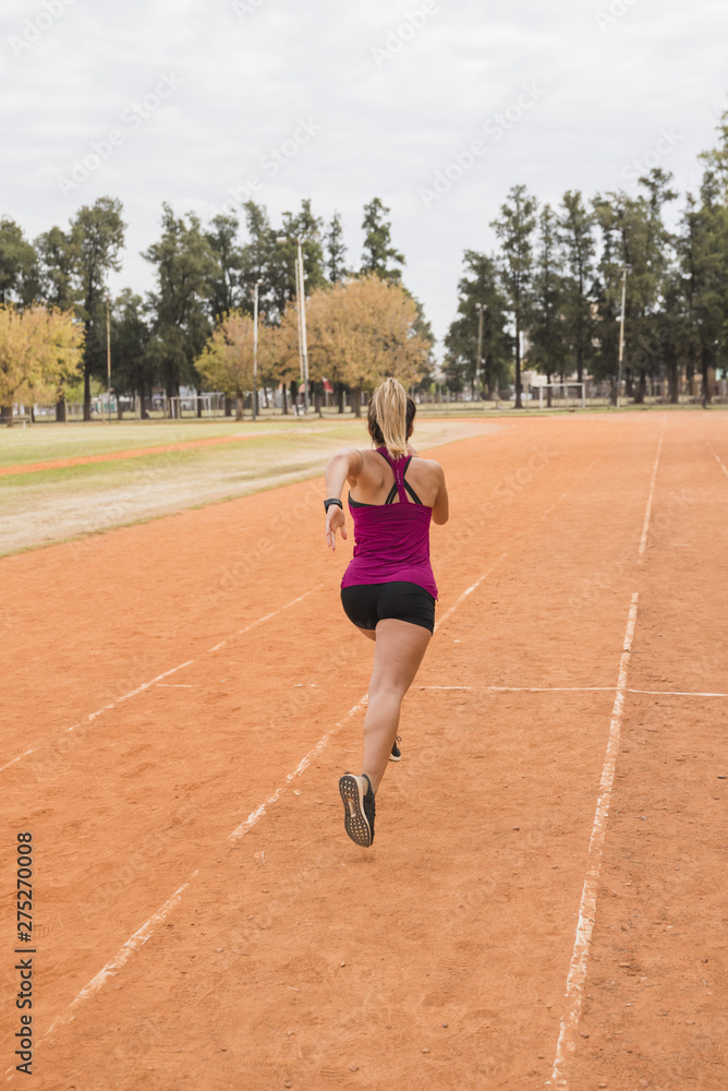 Obraz premium Sporty woman running on stadium track