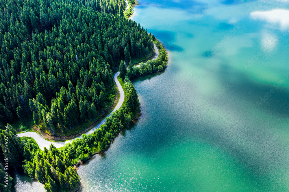 Aerial view over beautiful turquoise mountain lake and green forest. Spring in the mountains. Green forest, mountain lake. Green pine and fir trees forest and a lake. Beautiful mountain road. - Image