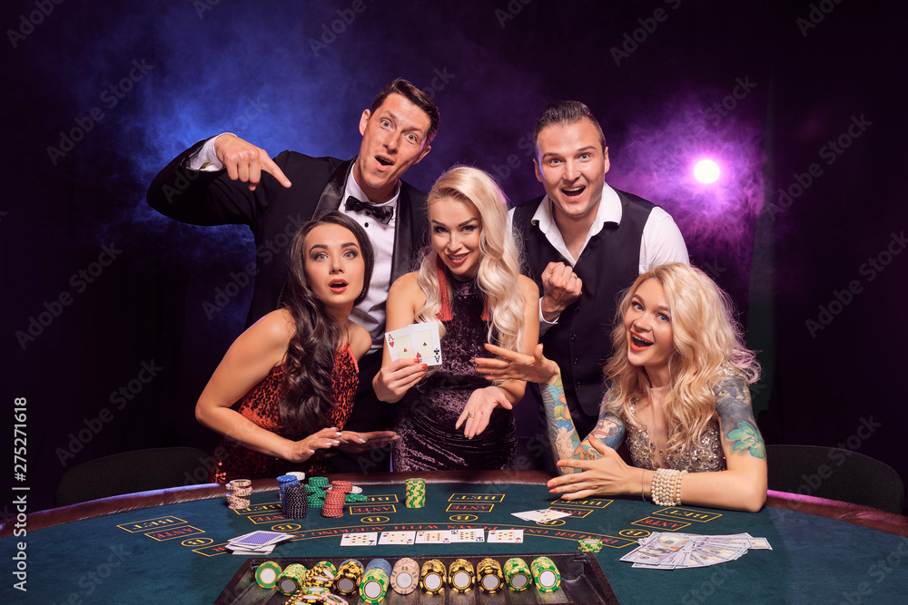 Group of a young wealthy friends are playing poker at a casino ...