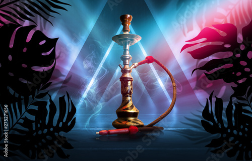 Smoking hookah on a dark abstract background, neon light. Silhouettes of tropical palm leaves in the foreground.