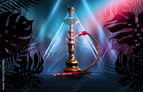 Smoking hookah on a dark abstract background, neon light. Silhouettes of tropical palm leaves in the foreground.