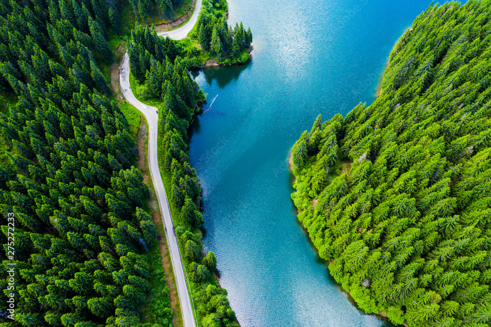 Aerial view over beautiful turquoise mountain lake and green forest. Spring in the mountains. Green forest, mountain lake. Green pine and fir trees forest and a lake. Beautiful mountain road. - Image