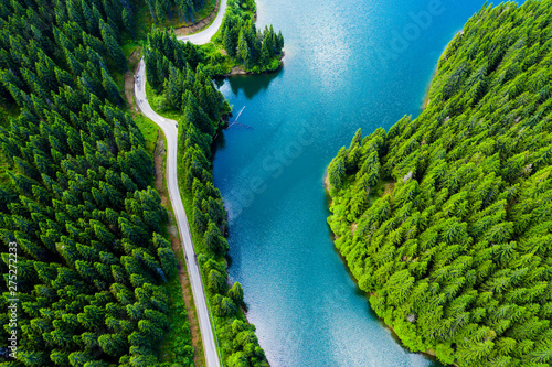 Obraz na płótnie Aerial view over beautiful turquoise mountain lake and green forest. Spring in the mountains. Green forest, mountain lake. Green pine and fir trees forest and a lake. Beautiful mountain road. - Image w salonie