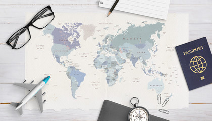 Concept of travel organization. Airplane model, passport, compass, glasses, pad and pencil on world map. Copy space in the middle. Top view, flat lay.